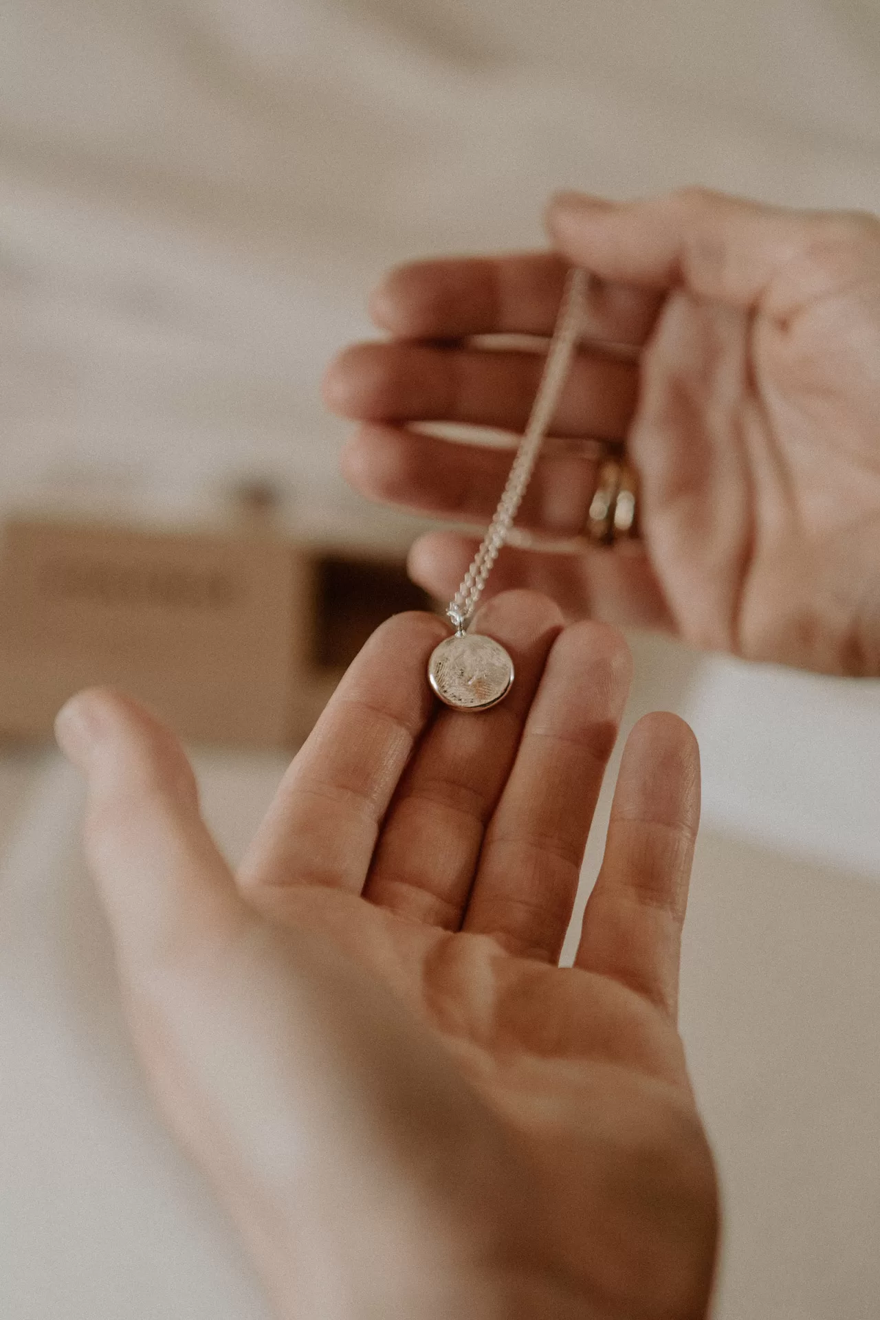 Woman holding a silver fingerprint impression necklace in their hands