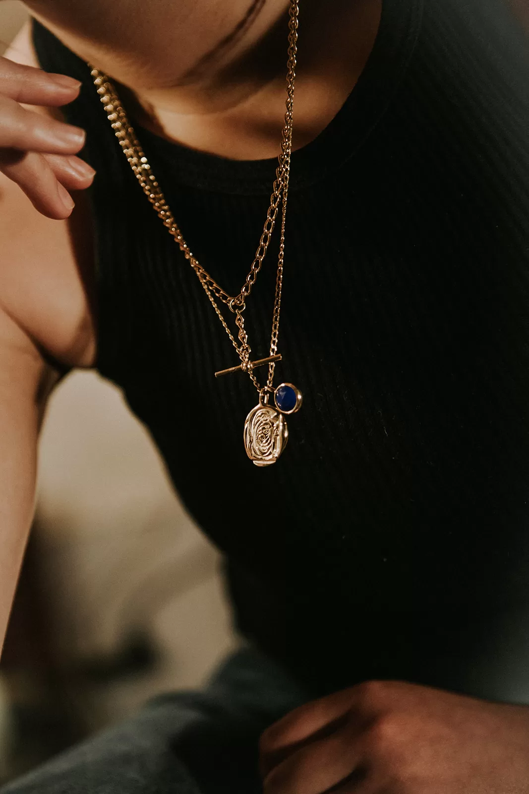 Woman wearing bespoke necklace with impression and gems on it from coveted jewellery