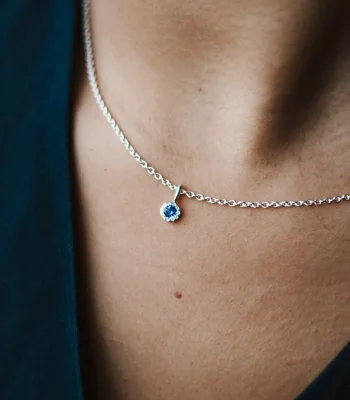 Close up of a model wearing a silver chain with a tanzanite birthstone pendant.