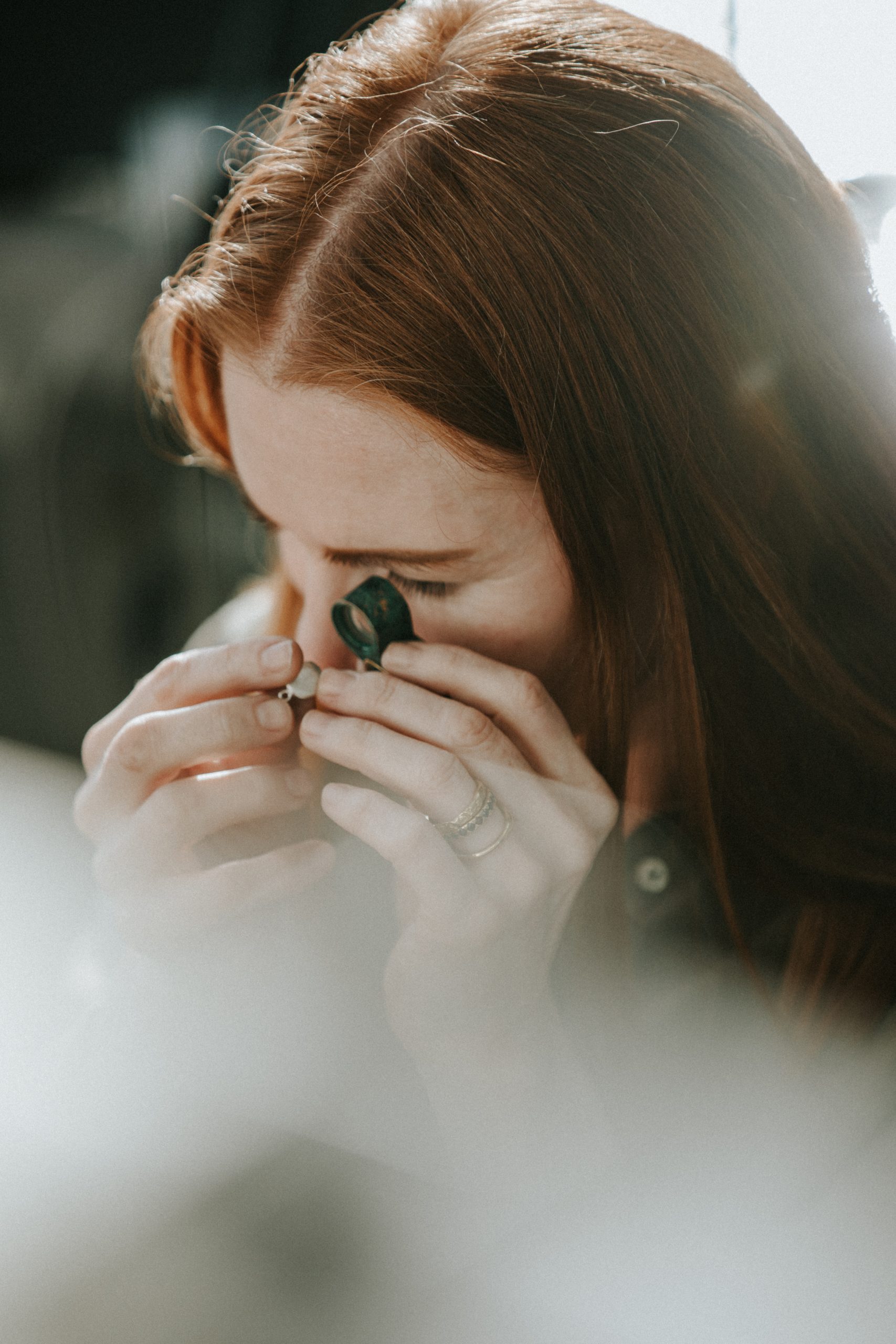 Image of GG looking at an impression pendant through a loupe.