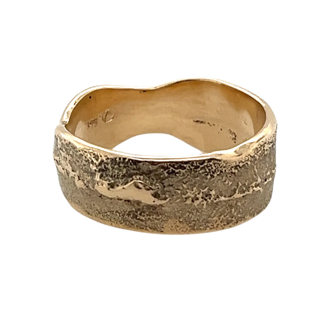 Image of a gold cigar ring. The ring has lots of textured details including darker and lighter areas and shiny edges.
